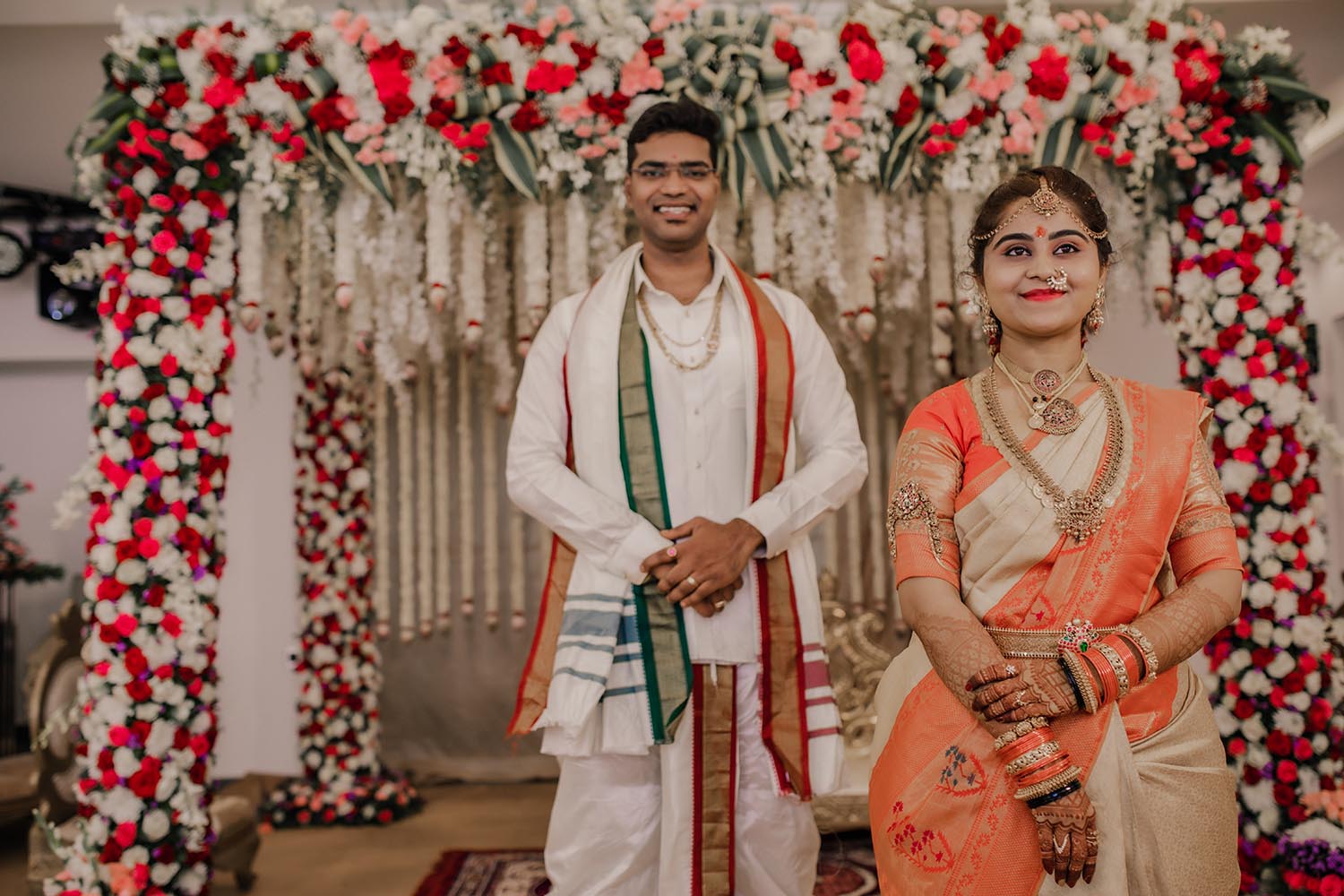 bride and groom on their naidu wedding day in the backdrop of flowered decoration